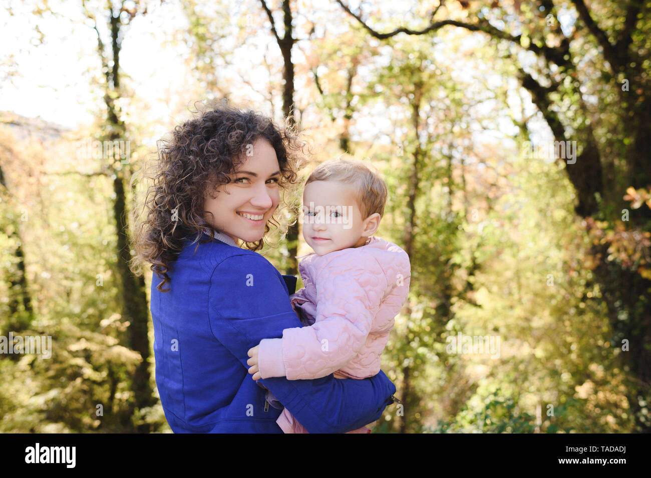 Portrait of happy mother carrying her daughter in nature Stock Photo