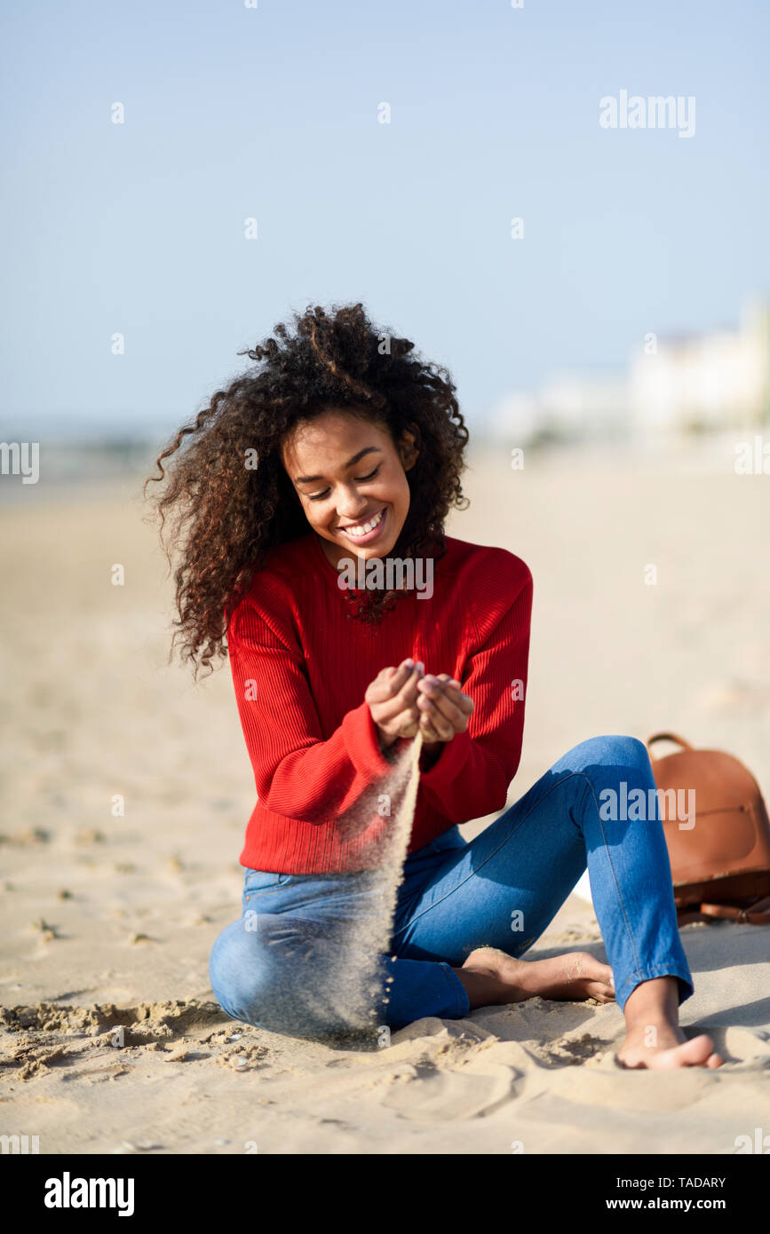 Happy young woman sitting on the beach Stock Photo - Alamy