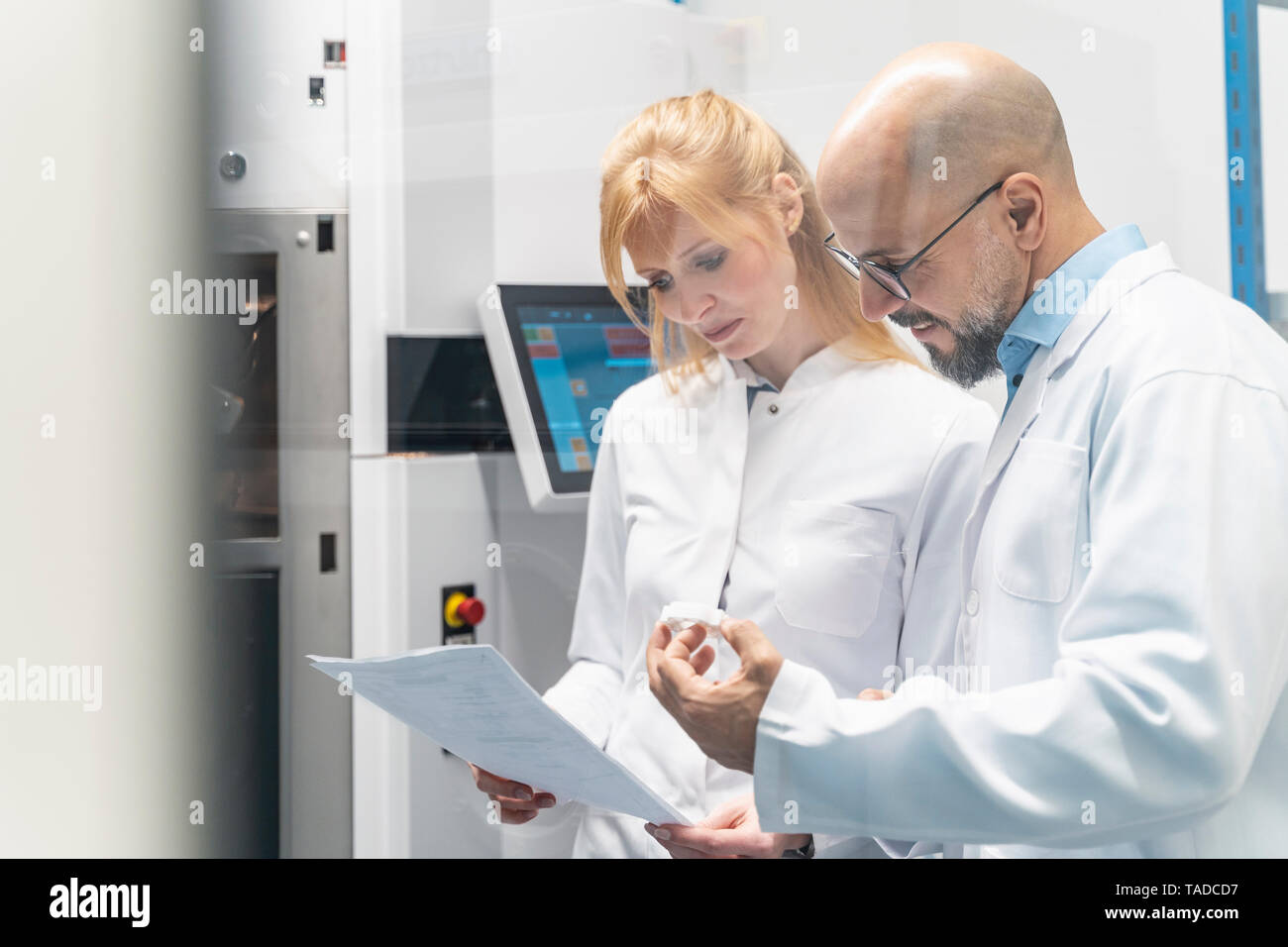 Two technicians wearing lab coats looking at plan Stock Photo