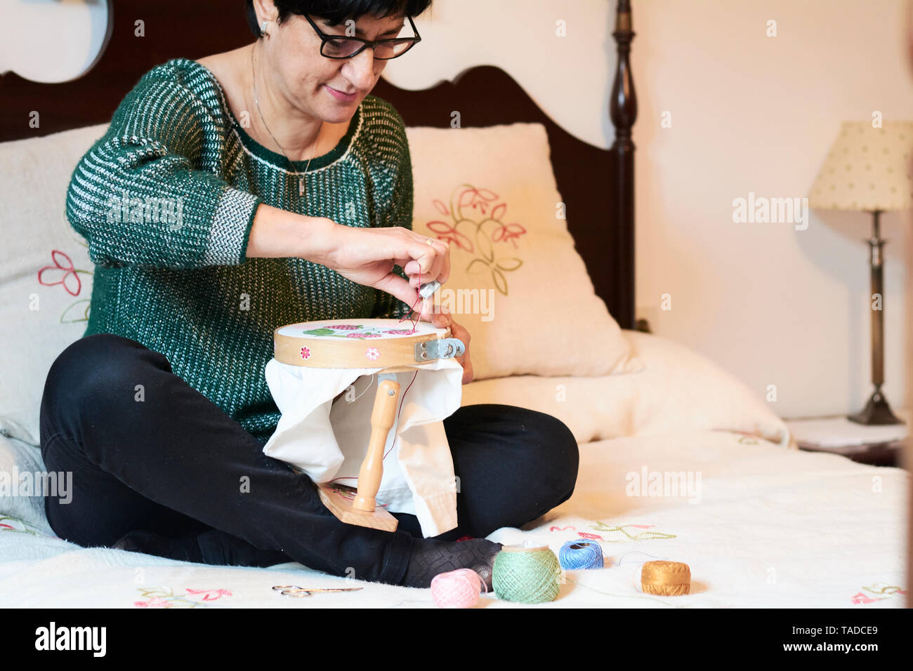 Woman embroidering sitting on bed at home Stock Photo