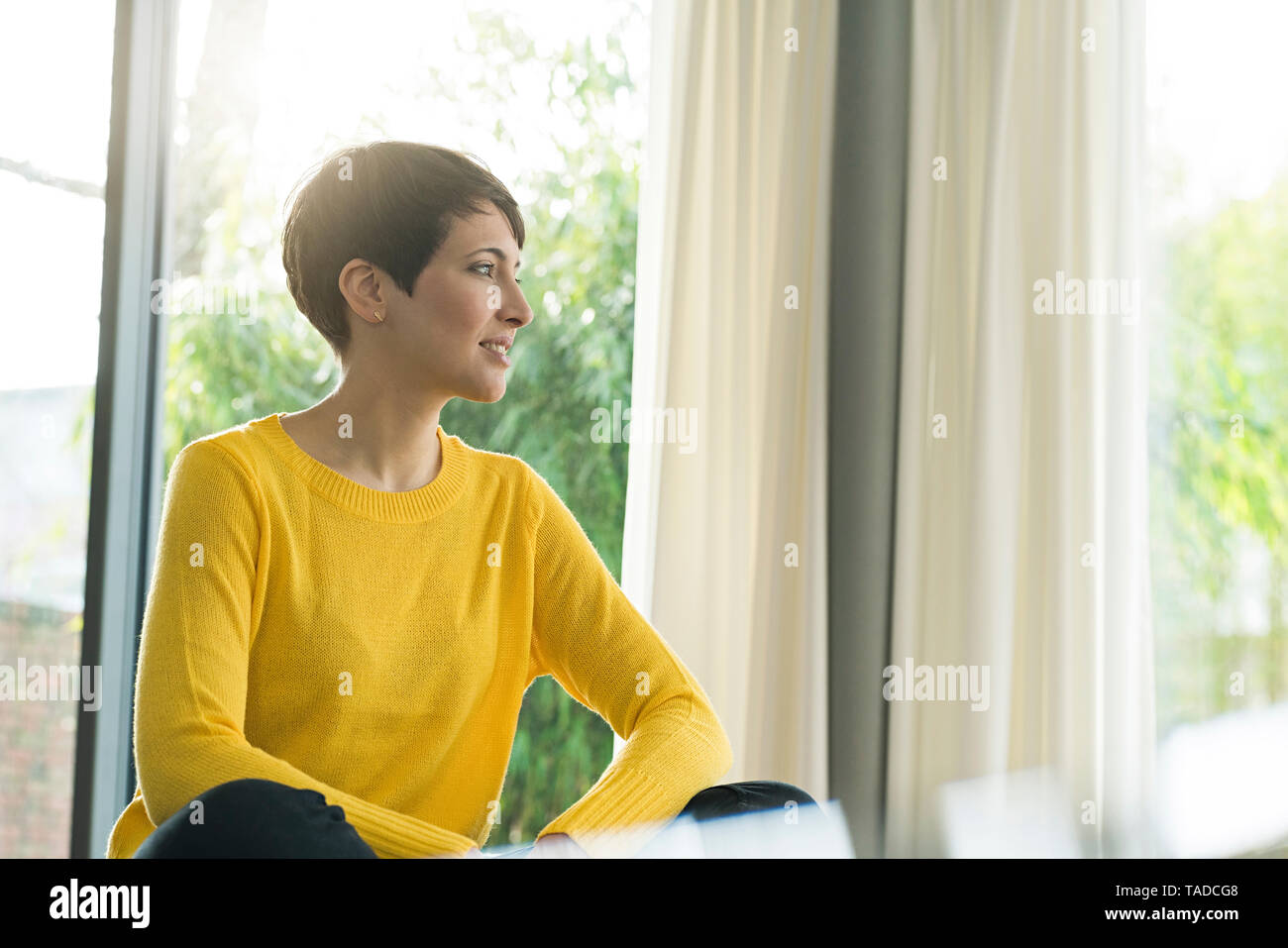 Woman sitting in the living room  looking out of window Stock Photo