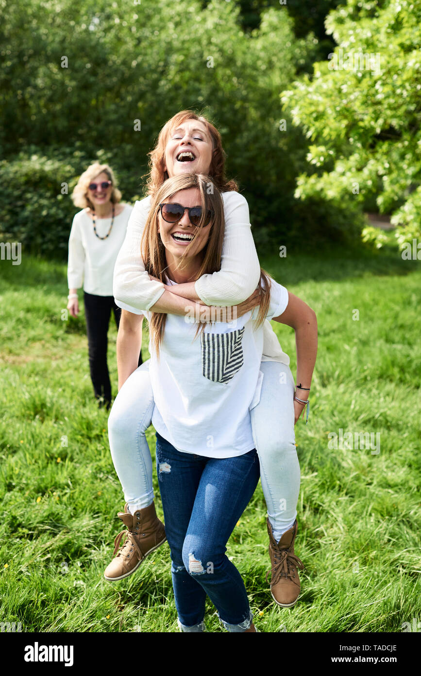 Happy young woman carrying mother piggyback in park Stock Photo