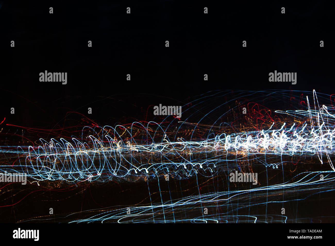 Different light trails of multicolored street lanterns and passing cars scattering in the dark, long exposure urban abstract background Stock Photo