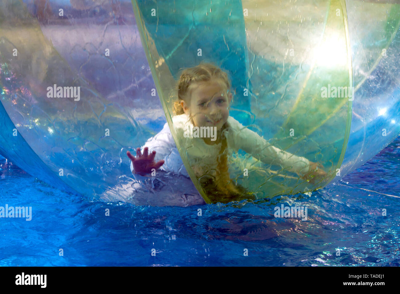 Little girl playing inside the big transparent water bubble in swimming pool Stock Photo