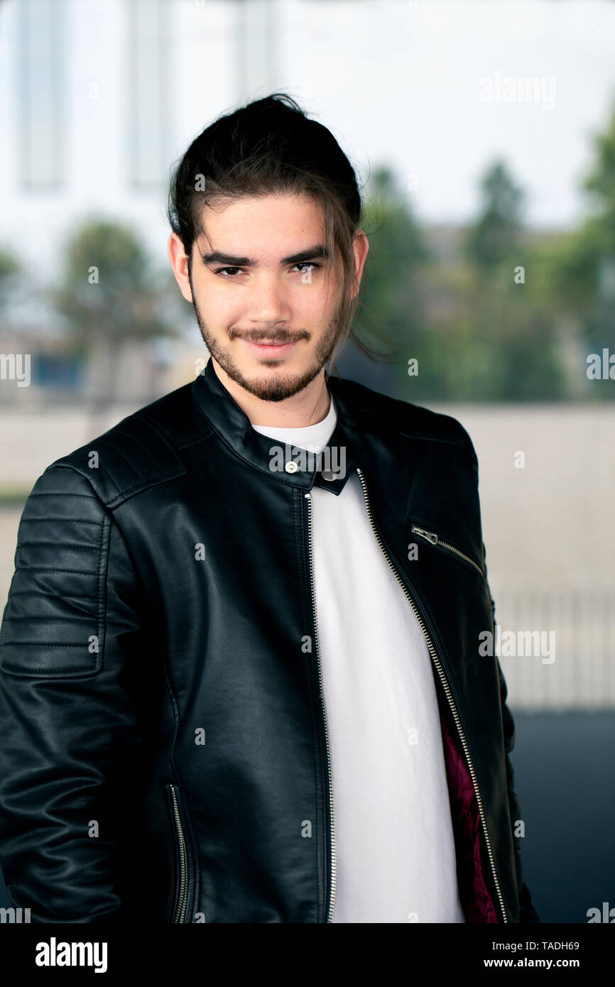 Half length portrait of handsome bearded man dressed in fashionable clothes standing on street against while wall background with area for advertising content.Handsome hipster guy posing on copy space Stock Photo