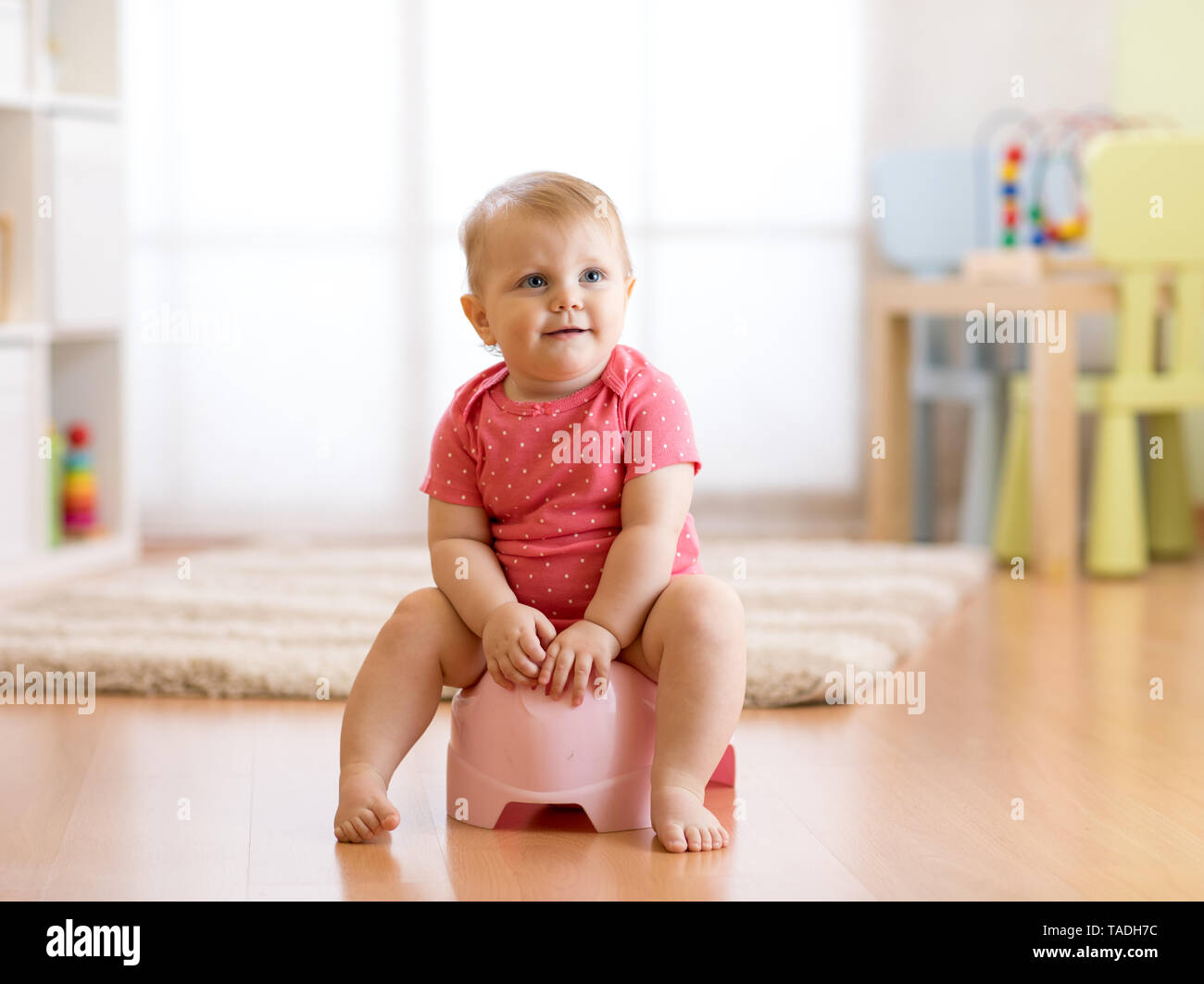 Toddler Girl On A Potty In The Living Room High-Res Stock Photo