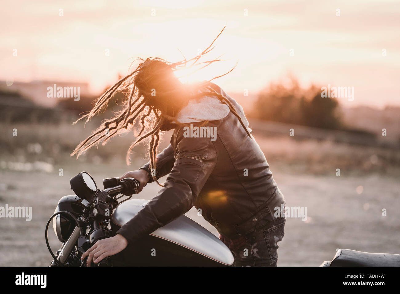 Biker tossing his dreadlocks at sunset Stock Photo
