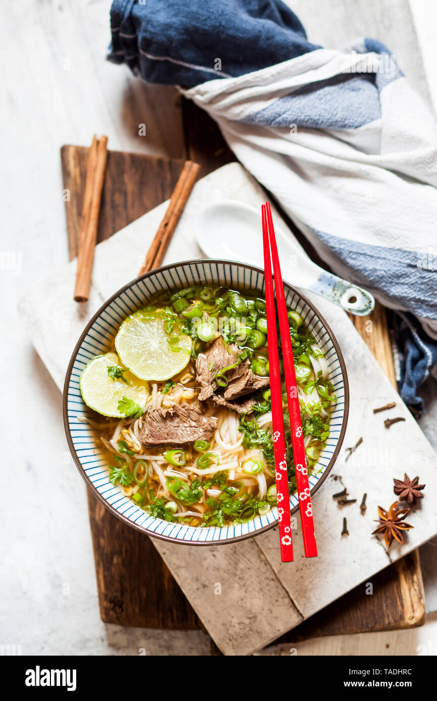 Bowl of Vietnamese Pho with rice noodles, mung beans, cilantro, spring onions and limes Stock Photo
