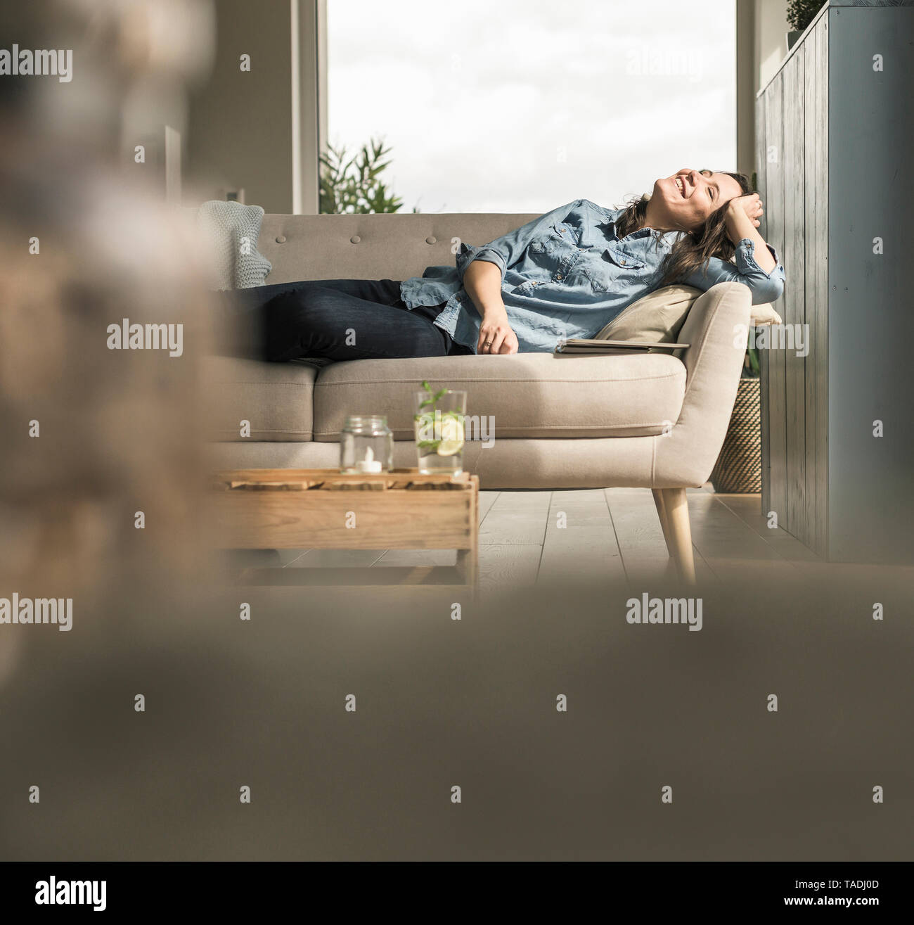 Happy woman lying on the couch at home Stock Photo - Alamy