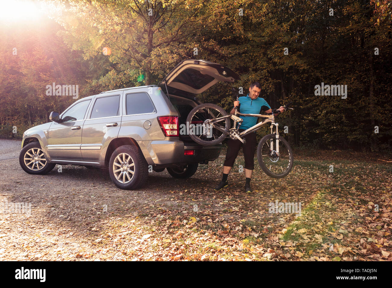 Man on foreat car park unloading mountainbike from car Stock Photo
