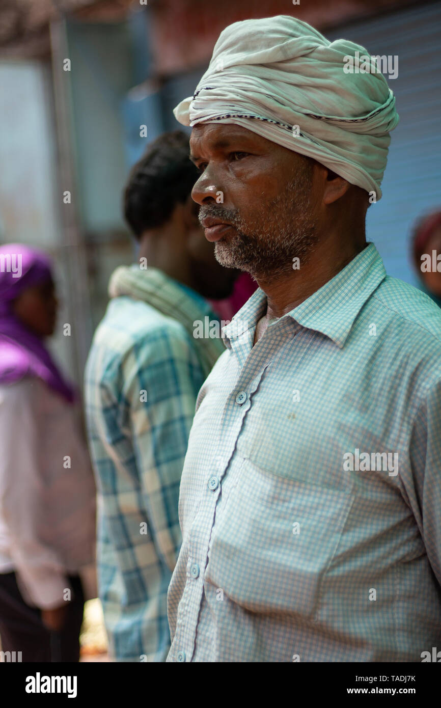 Serious Indian man with a beard staring into the distance with turban on his head waiting to make some sales at the Varanasi flower market. Stock Photo