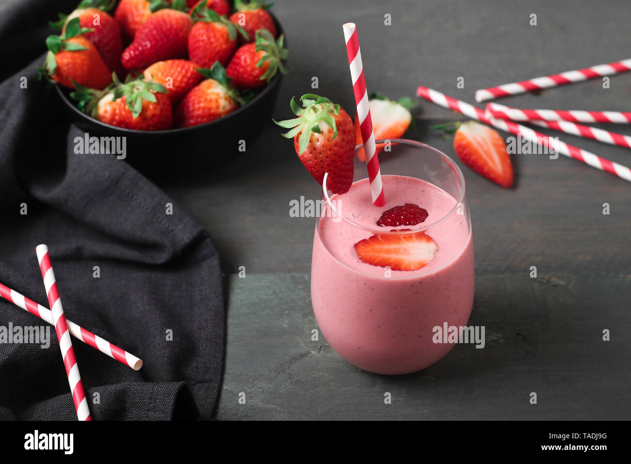 Glasses of strawberry smoothie and strawberries on dark wood Stock Photo