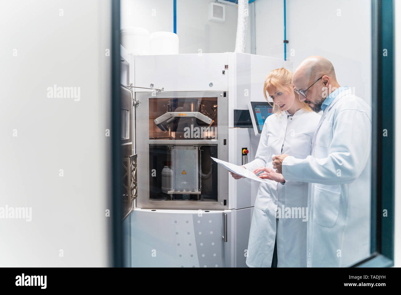 Two technicians wearing lab coats looking at plan Stock Photo