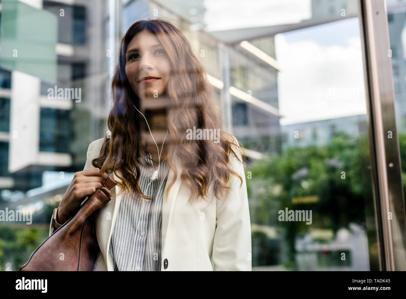Young businesswoman communting in the city, using earphones Stock Photo