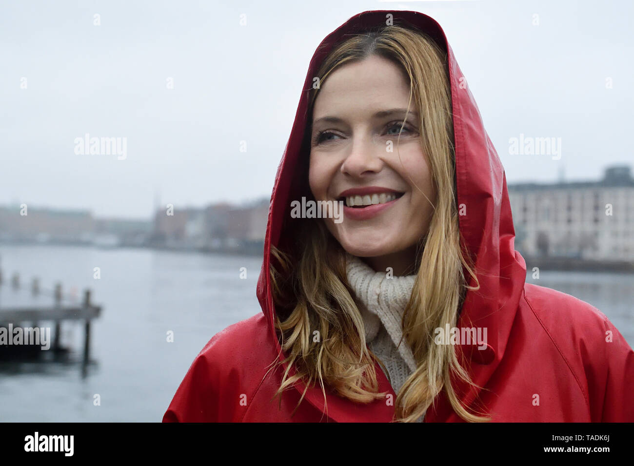 Denmark, Copenhagen, portrait of happy woman at the waterfront in rainy ...