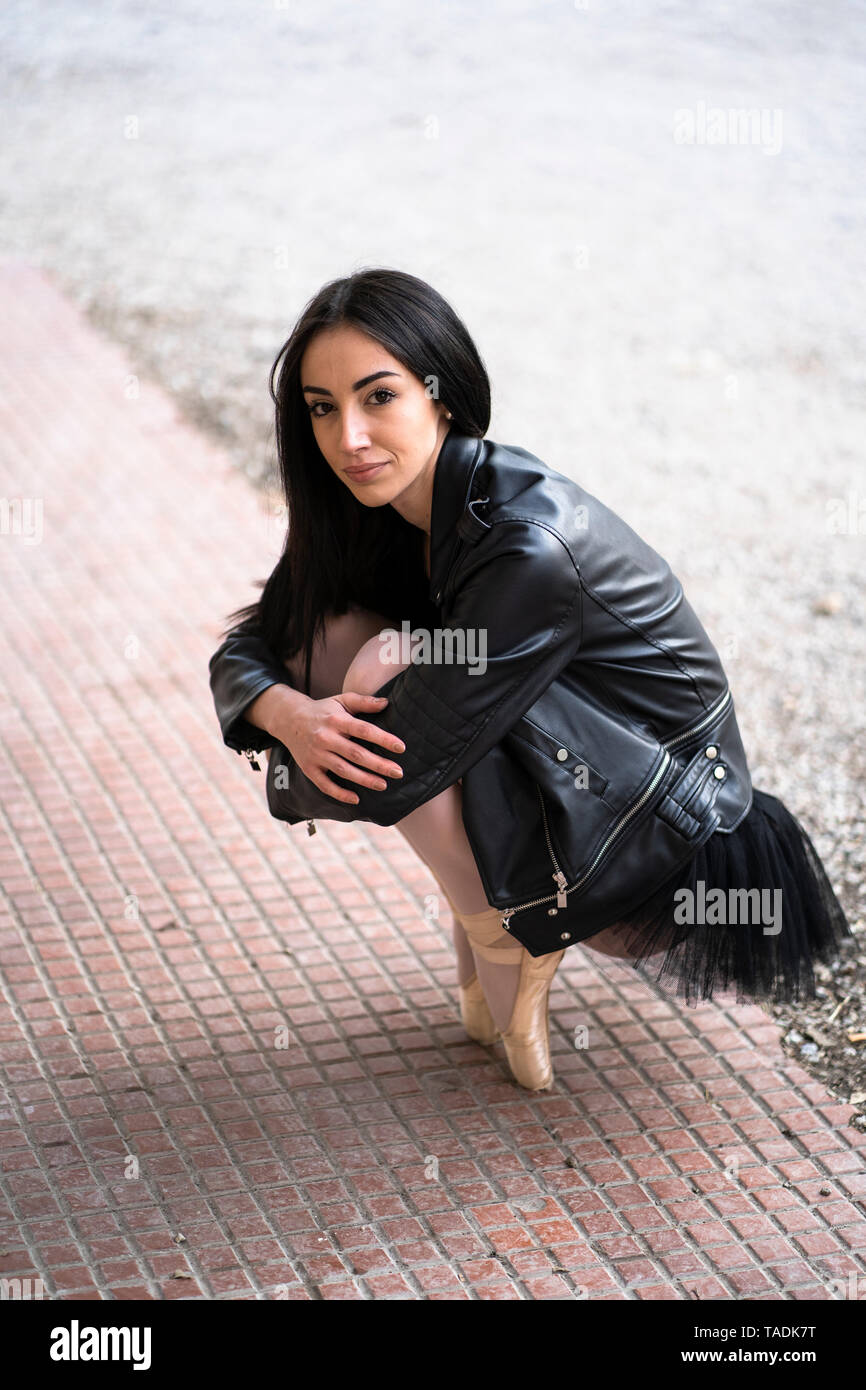 Portrait of young woman on tiptoes wearing leather jacket and tutu Stock Photo