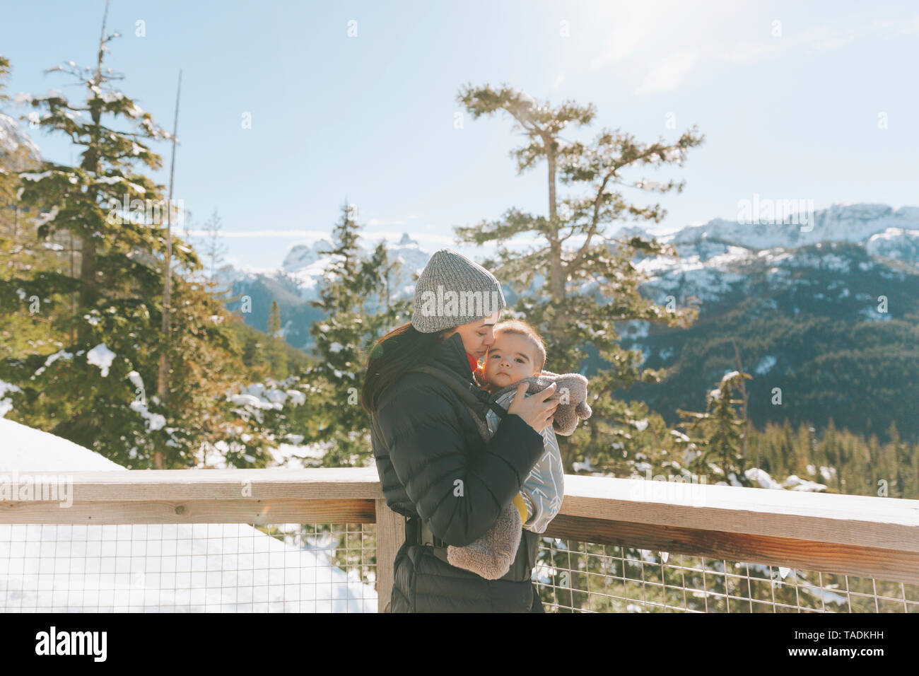Mother holding her baby son on an observation deck, looking over Squamish, Canada Stock Photo