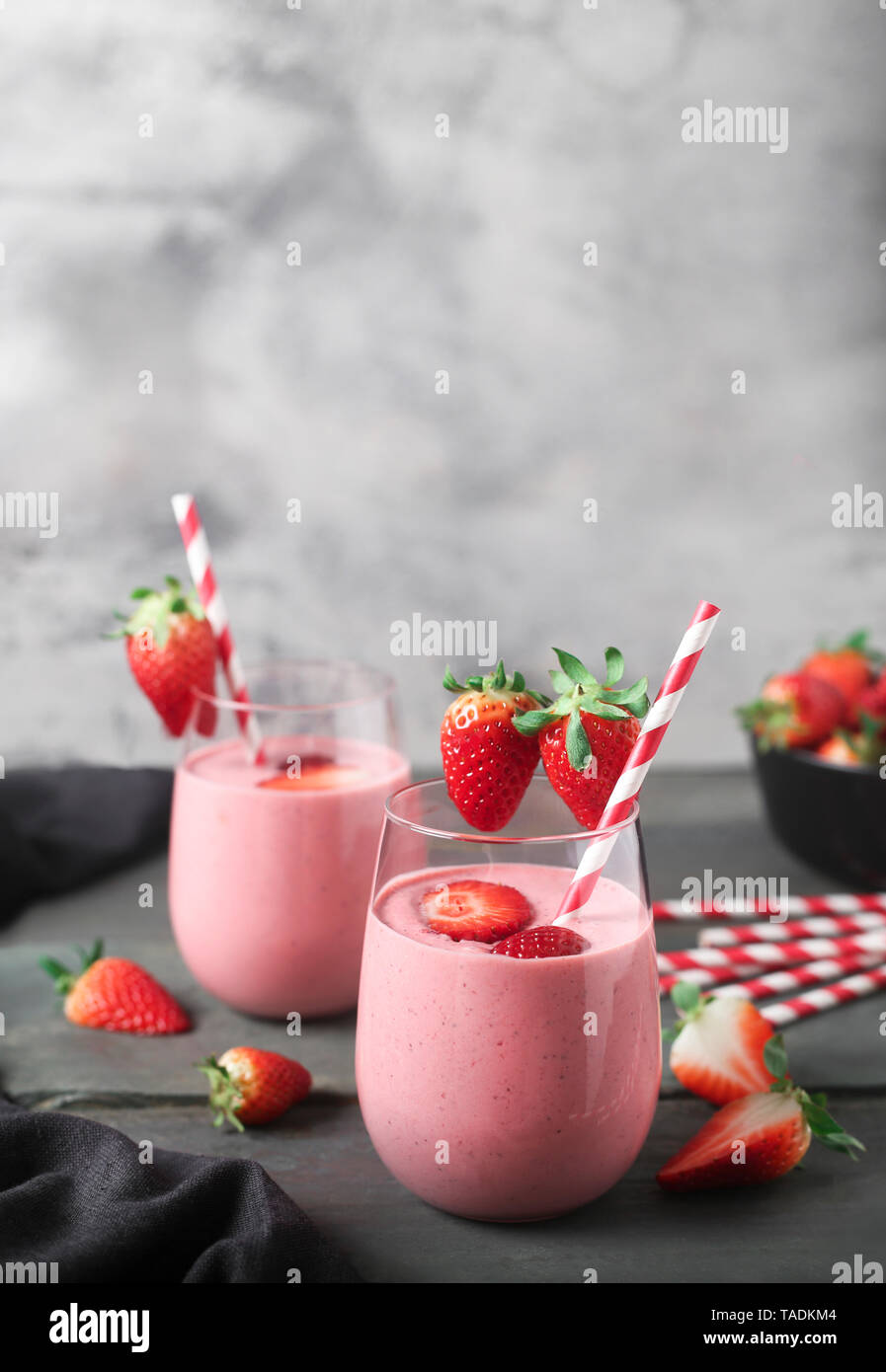 Glasses of strawberry smoothie and strawberries on dark wood Stock Photo