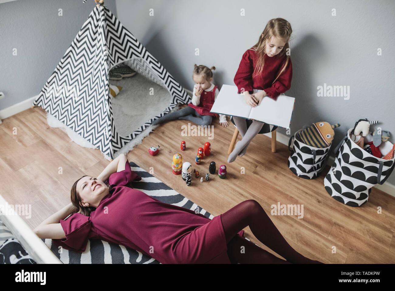 Mother relaxing with two girls in children's room at home Stock Photo