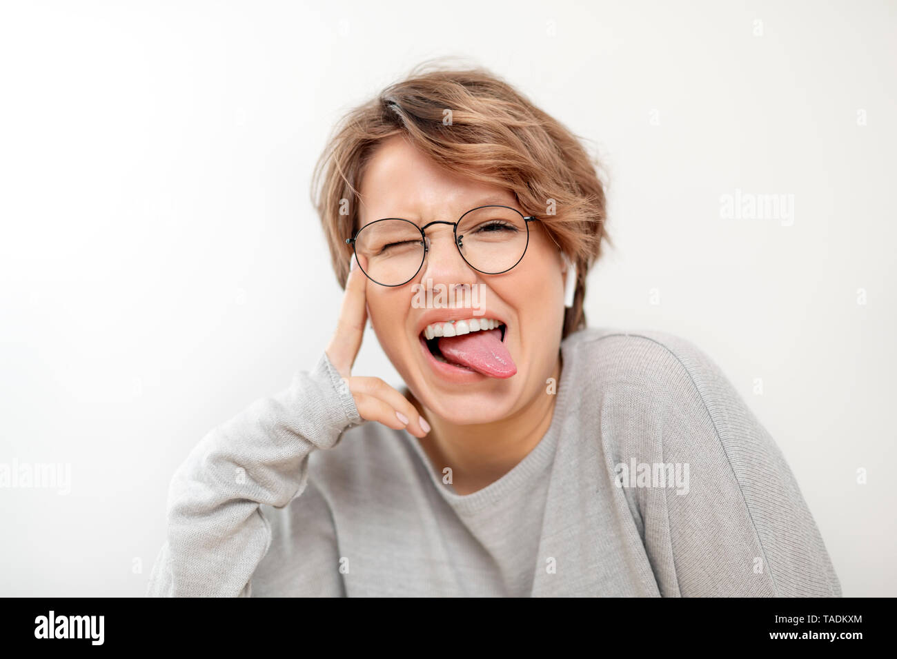 Portrait of young woman with wireless earphones pulling funny faces Stock Photo