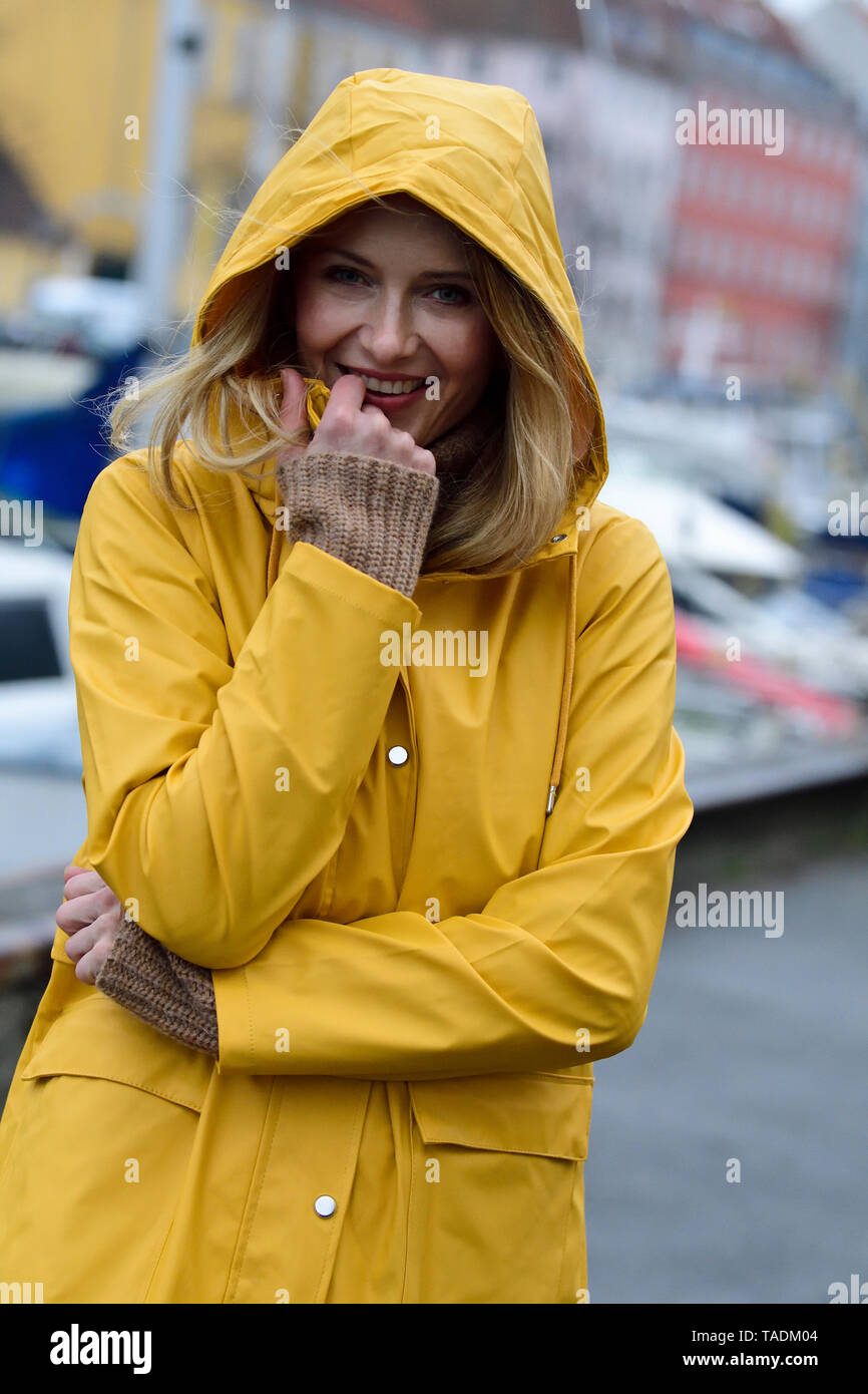 Denmark, Copenhagen, portrait of happy woman at city harbour in rainy weather Stock Photo