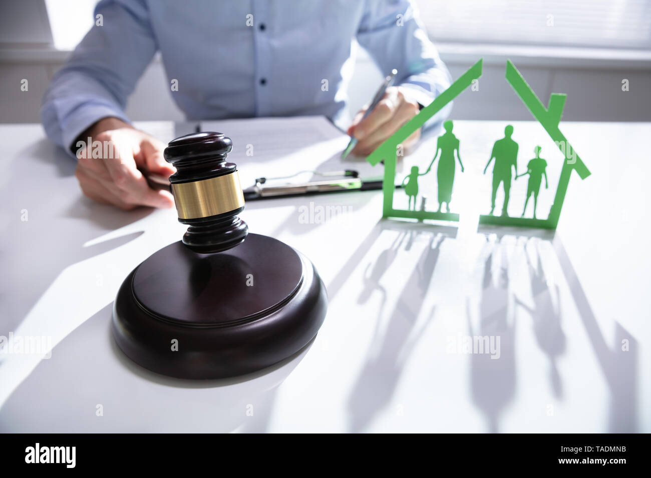 Close-up of mallet showing separation of family and house on desk Stock Photo