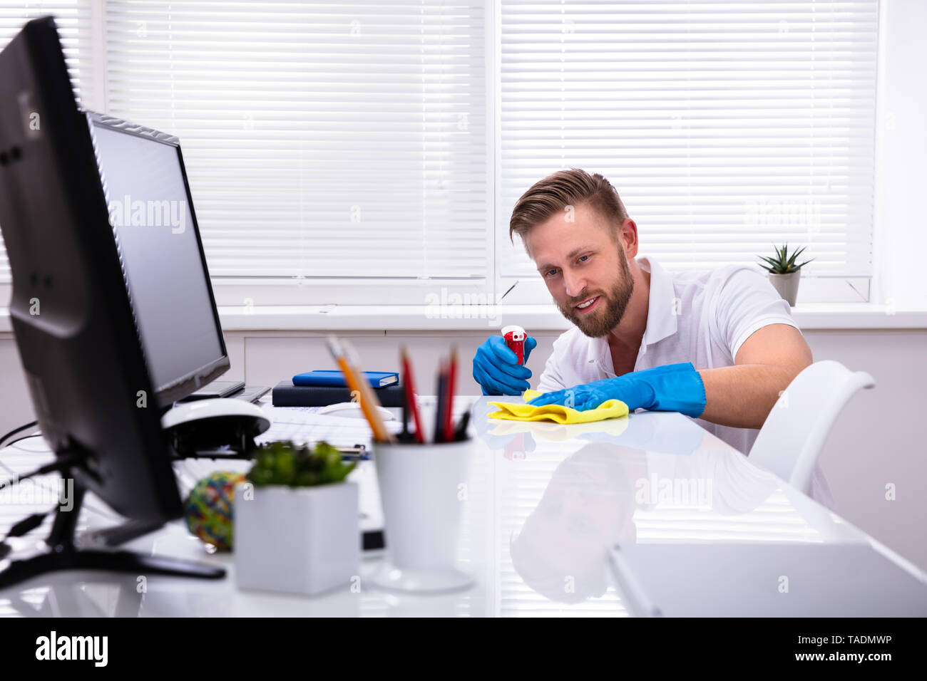 Janitor cleaning white desk in modern office Stock Photo Alamy