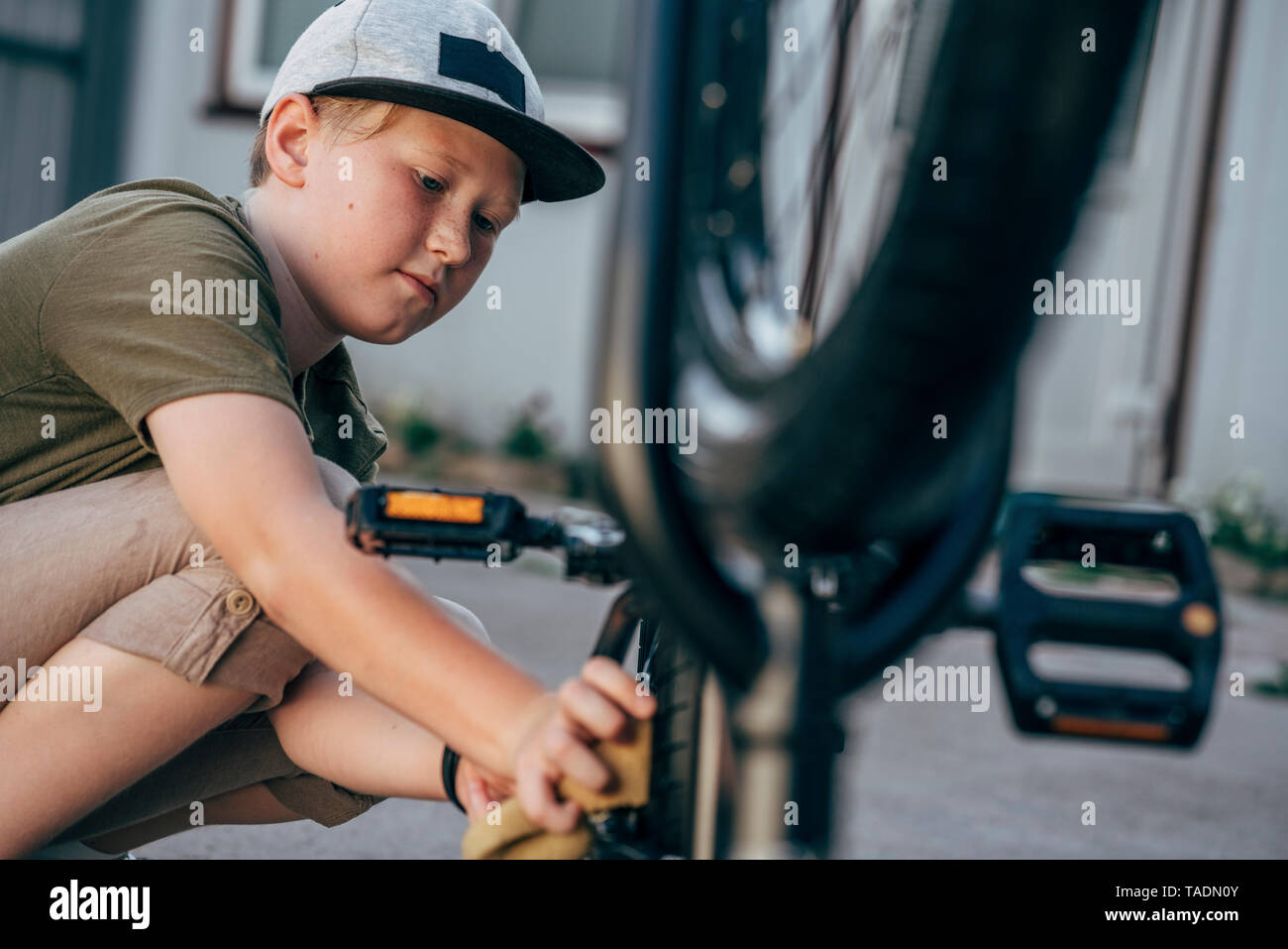 Boy cleaning bmx bike on yard Stock Photo