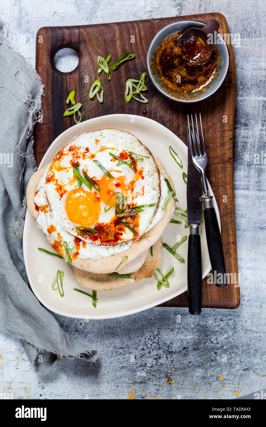 Flat bread with garlic yogurt, fried egg and chilli butter on chopping board Stock Photo