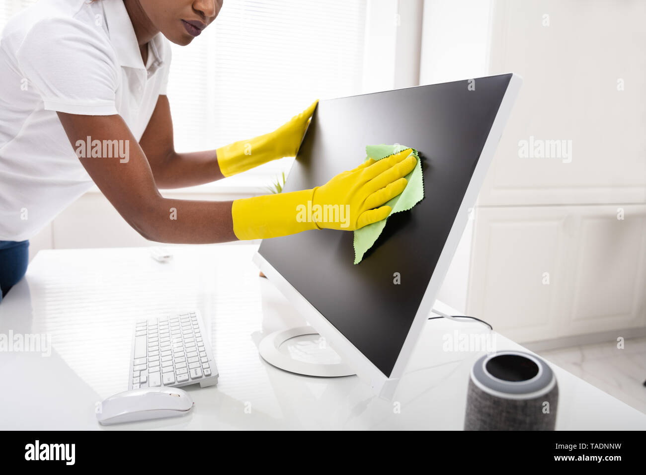 Close-up Of A Woman's Hand Cleaning Desktop Screen With Green Rag In Office Stock Photo