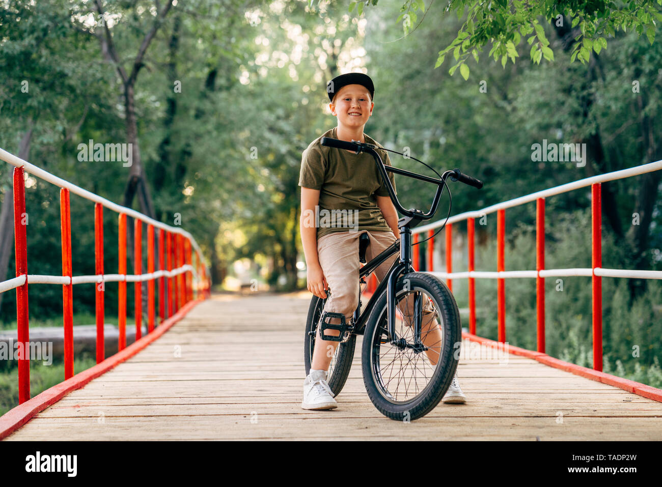 Portrait of smiling boy with bmx bike on bridge Stock Photo