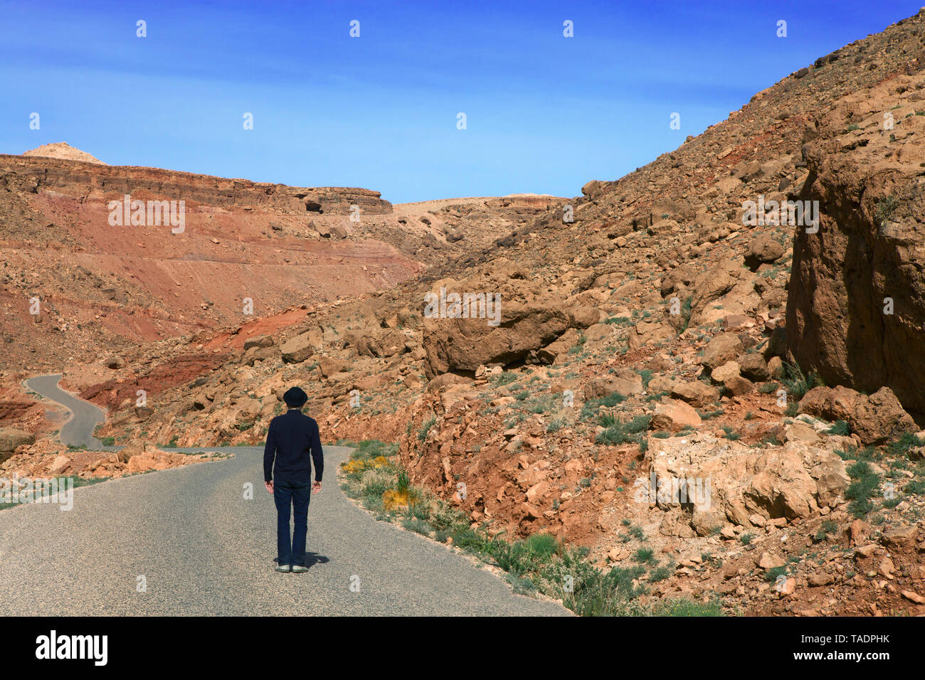 Morocco, Ounila Valley, rear view of man wearing a bowler hat standing on road in the mountains Stock Photo