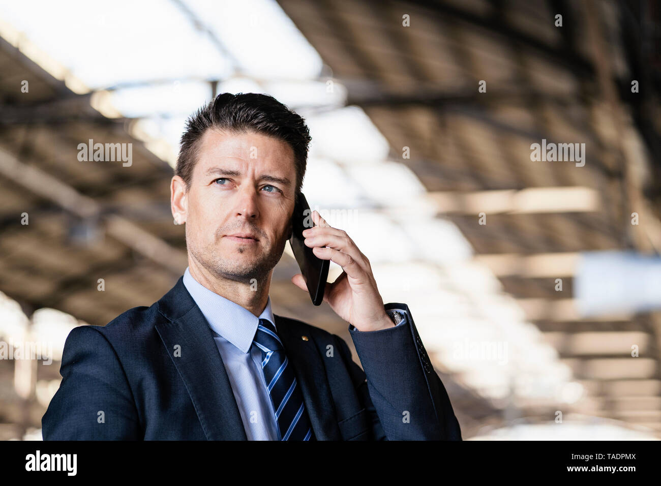 Businessman on cell phone at train station Stock Photo