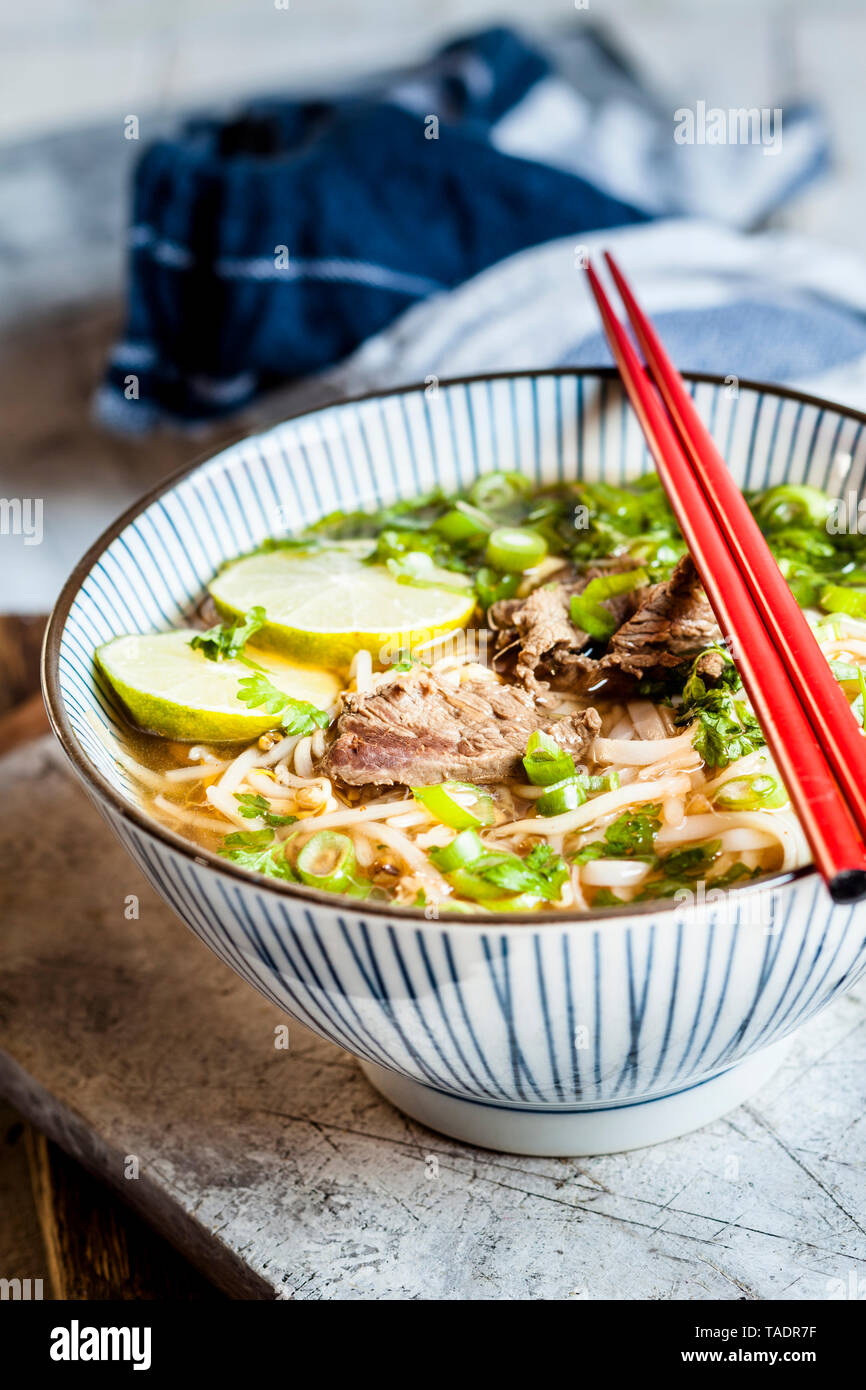 Bowl of Vietnamese Pho with rice noodles, mung beans, cilantro, spring onions and limes Stock Photo