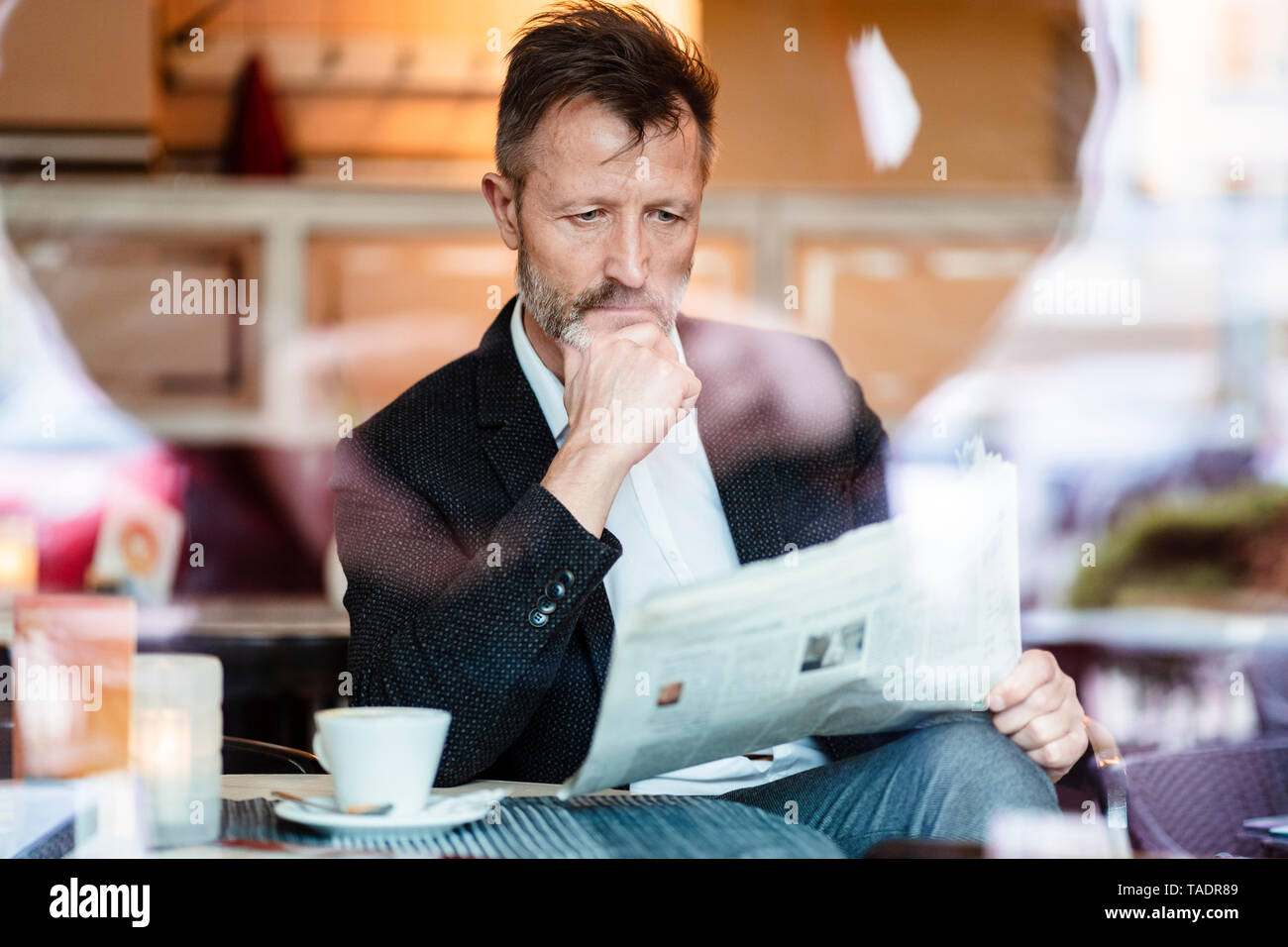 Portrait of pensive mature businessman reading newspaper in a coffee shop Stock Photo