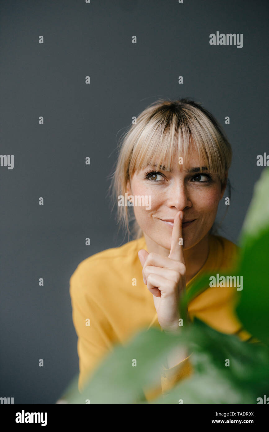 Portrait of a beautiful blond woman, smiling, putting finger on her mouth Stock Photo