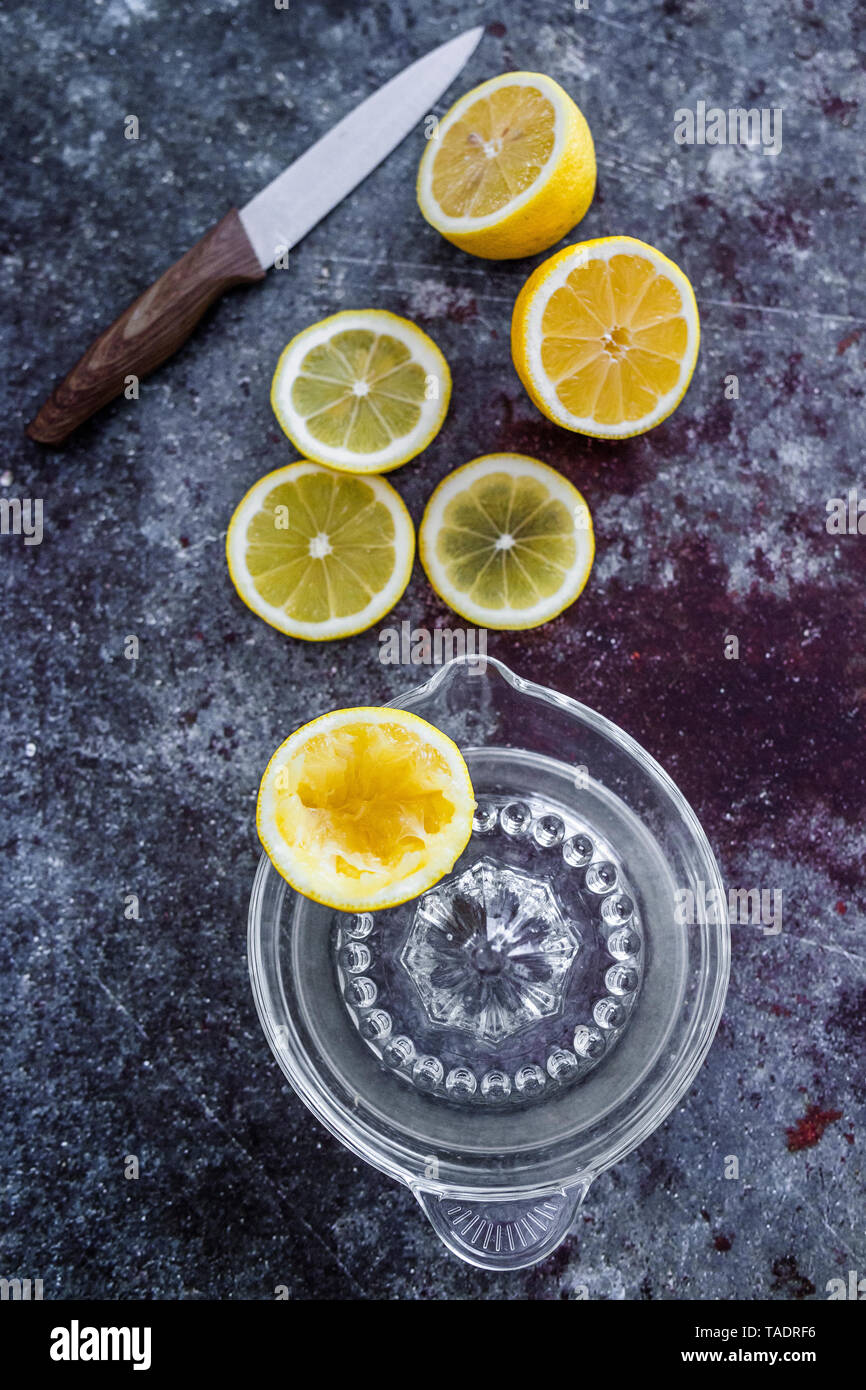 Lemon halves and slices and squeezed lemon half with litchen knide and lemon squeezer Stock Photo