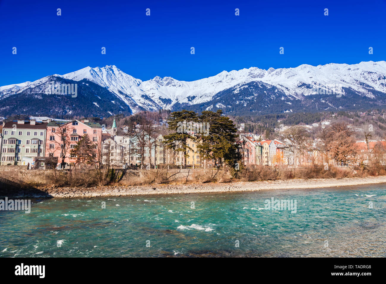 Austria, Tyrol, Innsbruck, colored buildings along the Inn river with snow-capped Alps in background Stock Photo