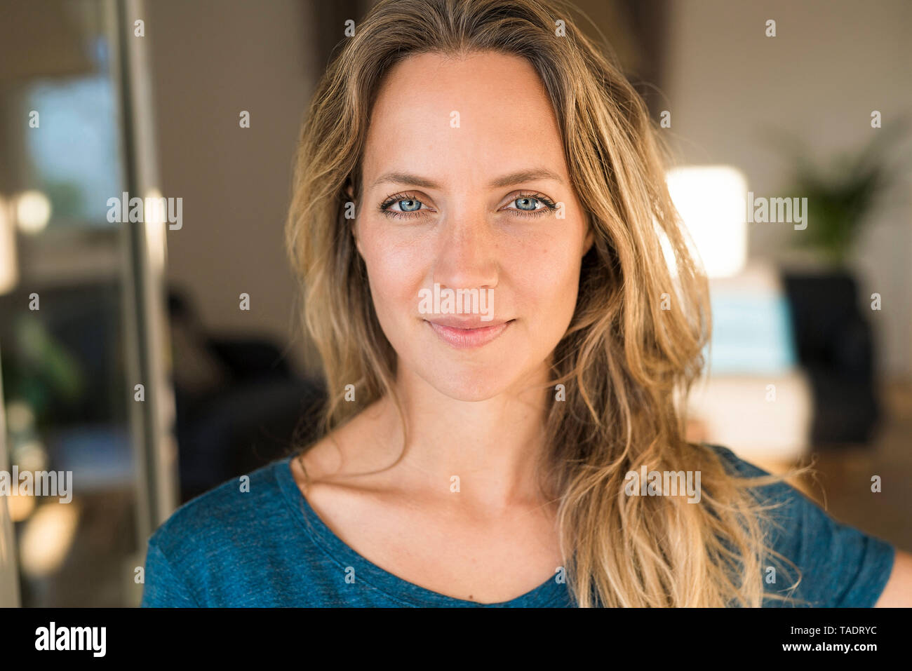 Portrait of smiling blond woman at home Stock Photo