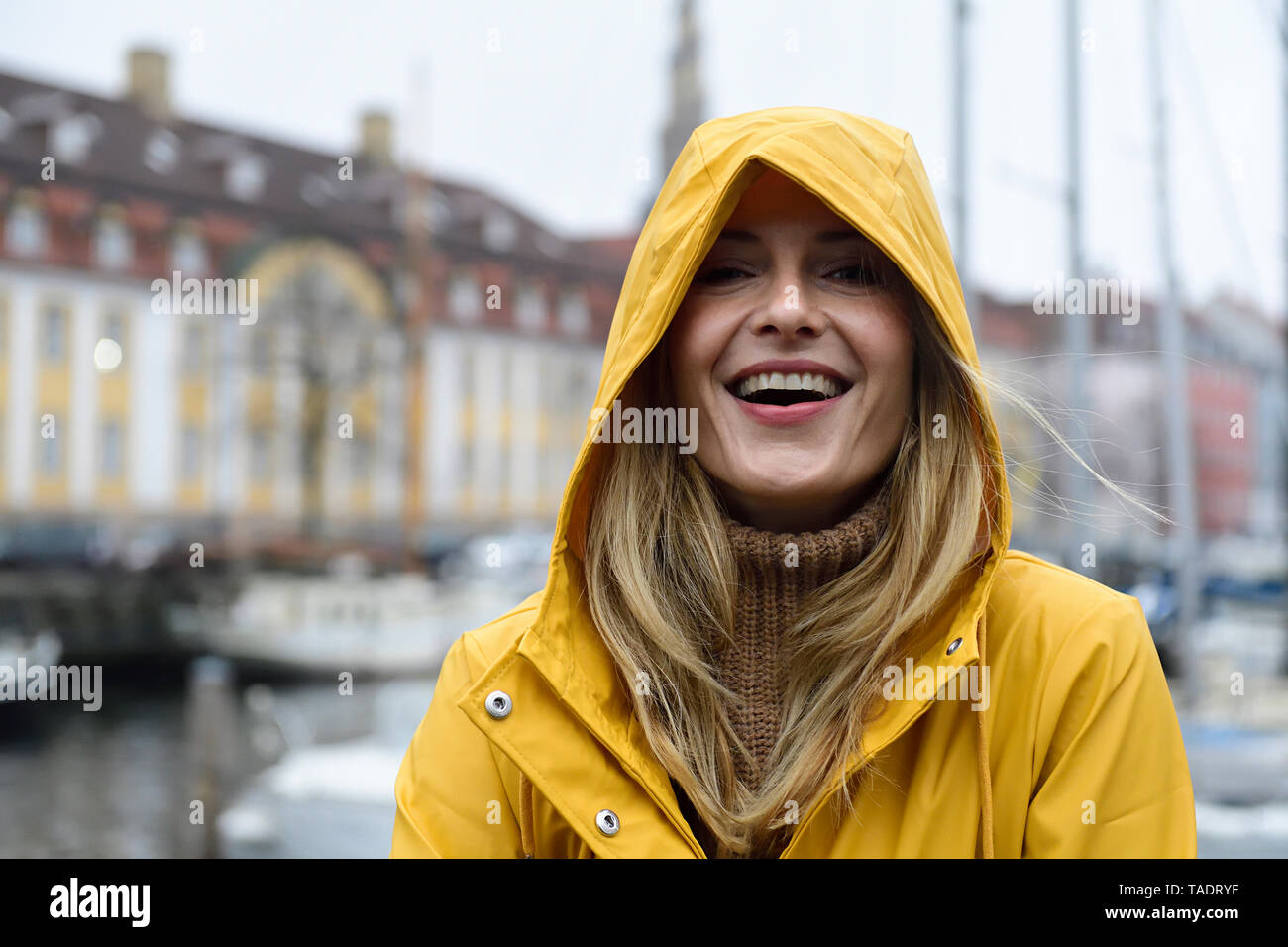 Denmark, Copenhagen, portrait of happy woman at city harbour in rainy ...