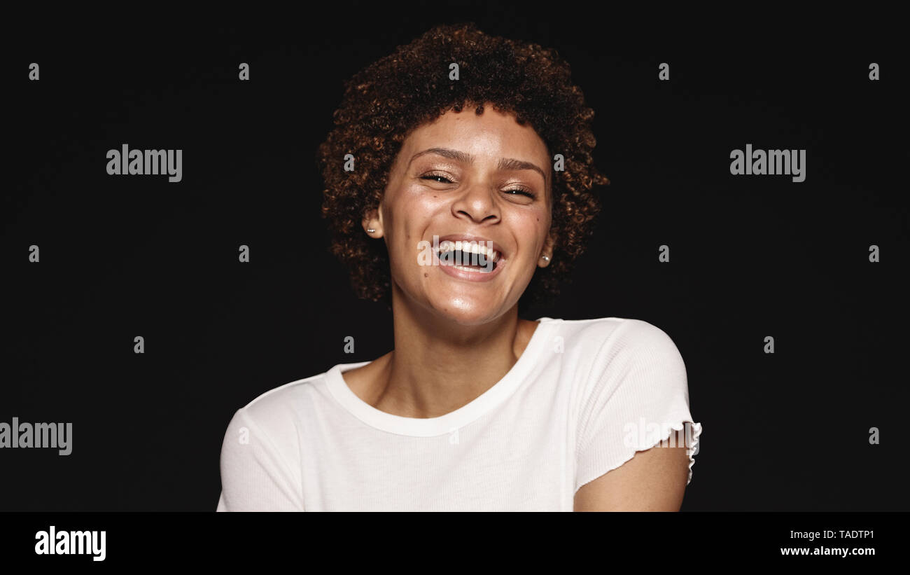 Portrait of a laughing young woman isolated on black background. Laughing woman looking at camera. Stock Photo