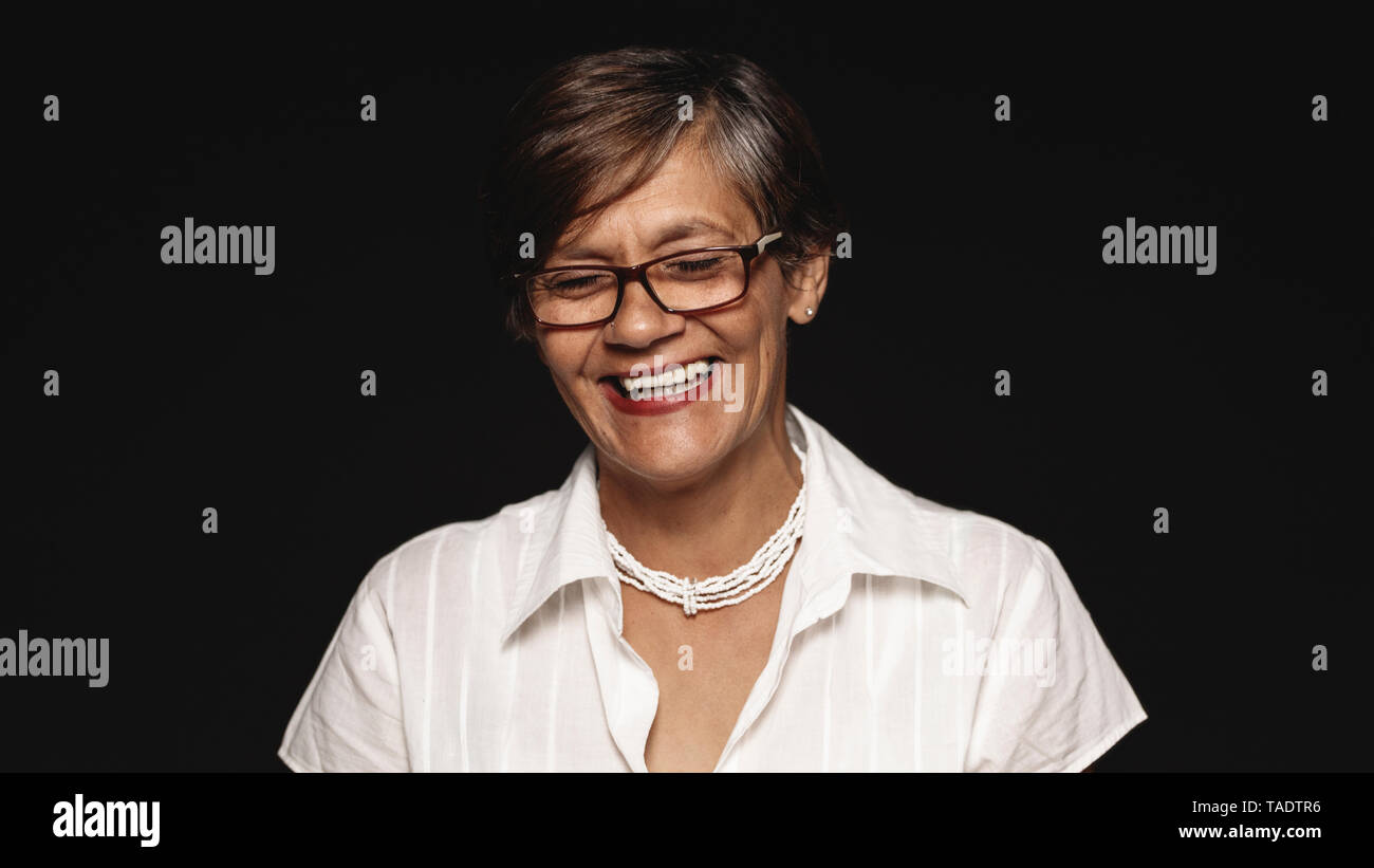 Close up of happy senior woman in eyeglasses laughing. Senior woman laughing with eyes closed isolated on black background. Stock Photo