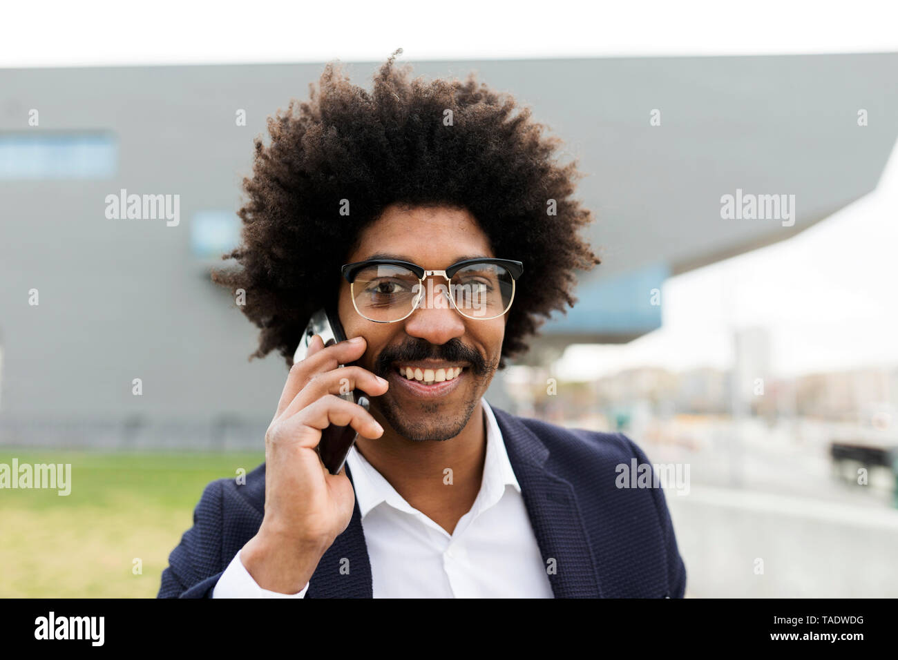 Spain, Barcelona, portrait of smiling businessman on cell phone in the city Stock Photo