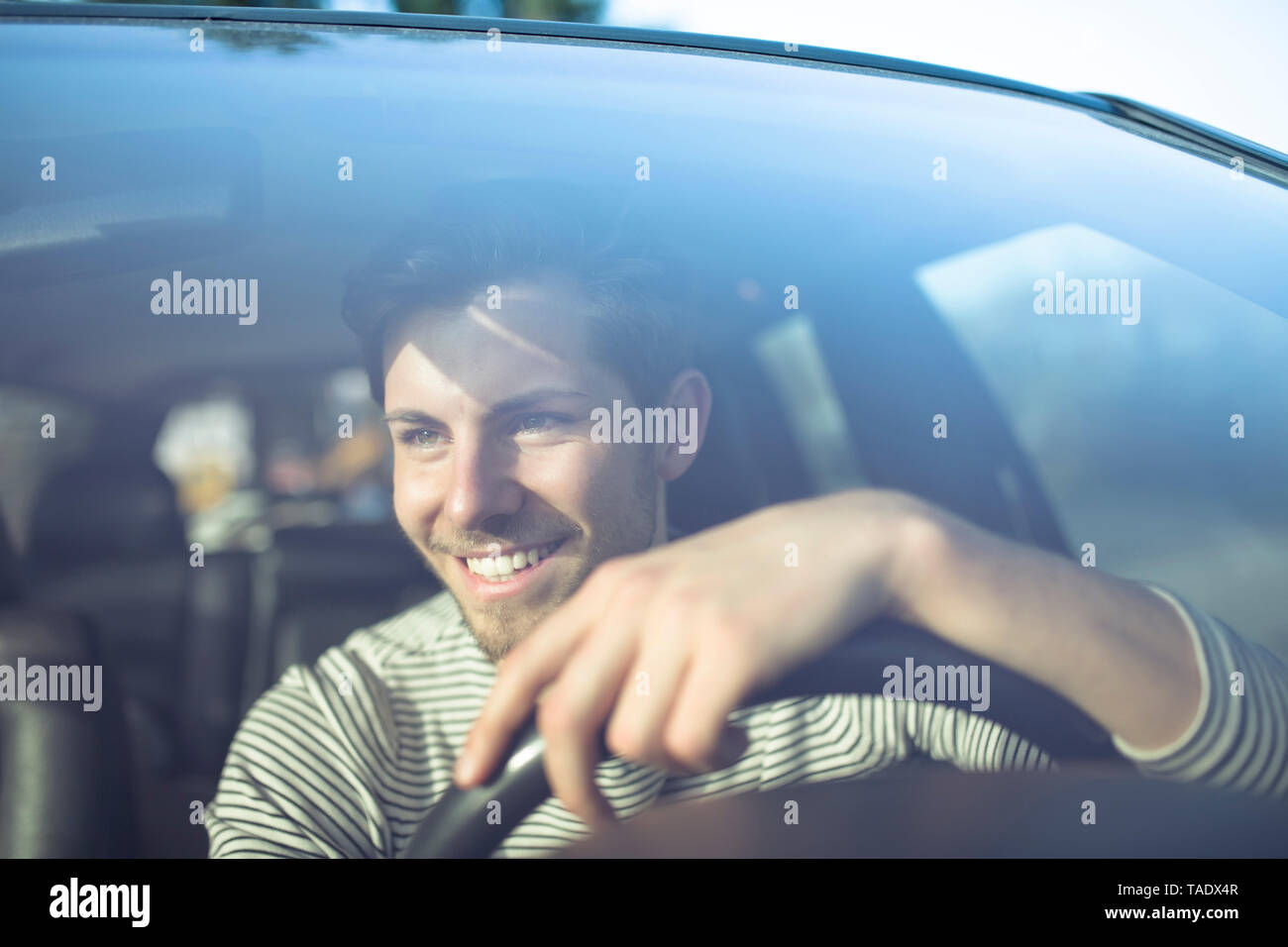 Smiling young man driving car Stock Photo