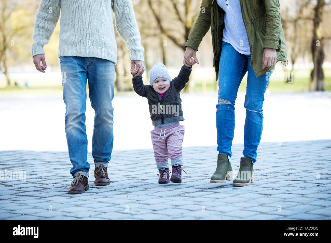 Portrait of girl walking hand in hand with parents Stock Photo