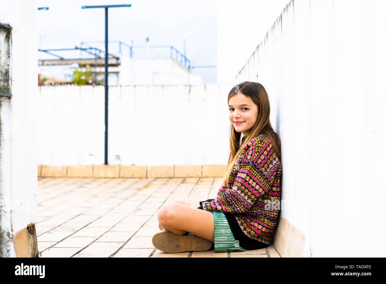 Portrait of smiling girl sitting on roof terrace Stock Photo - Alamy