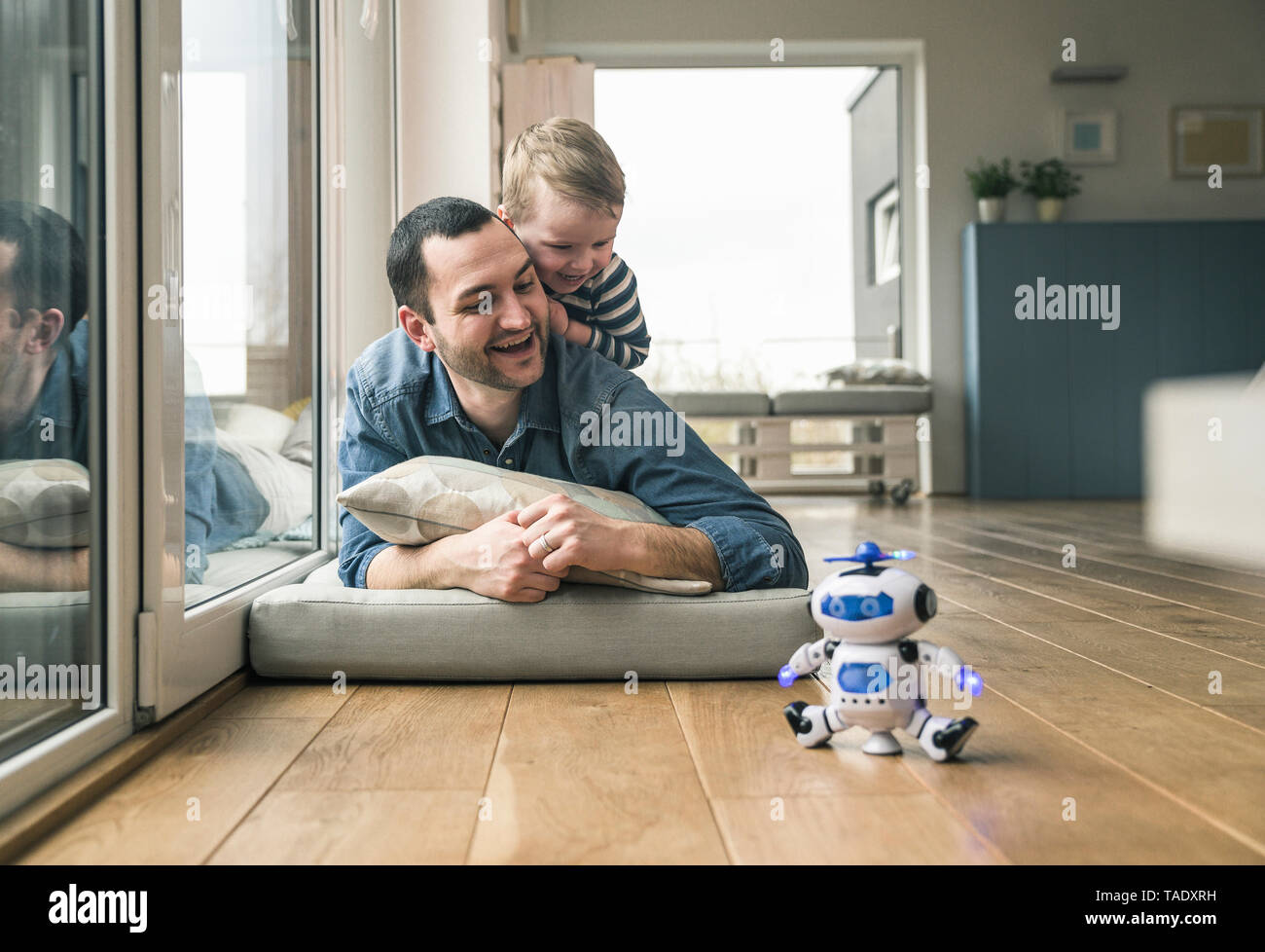 Excited father and son lying on a mattress at home watching a toy robot Stock Photo
