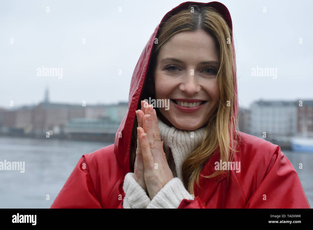 Denmark, Copenhagen, portrait of happy woman at the waterfront in rainy weather Stock Photo