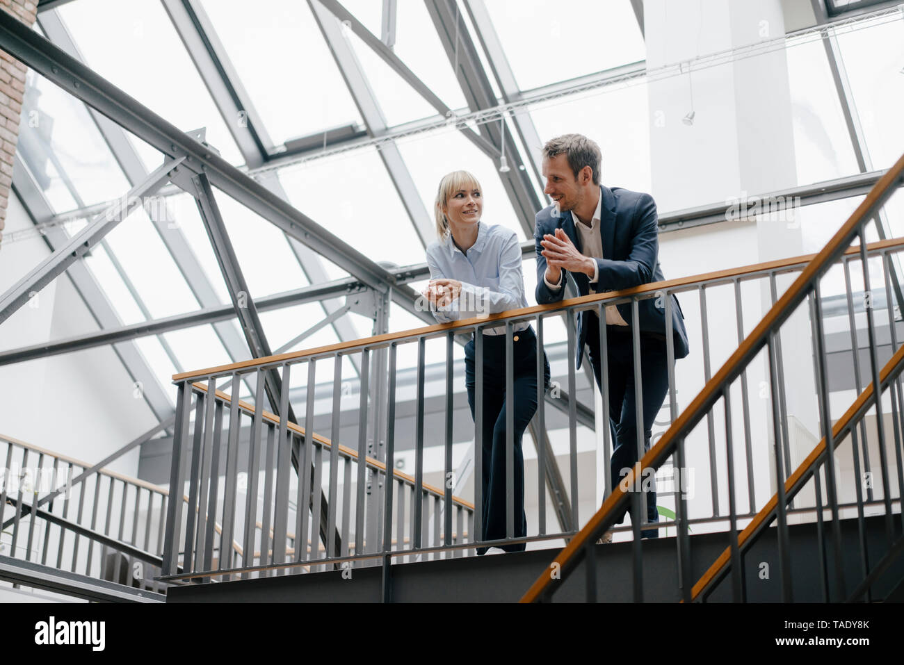 Businessman and woman standing in office building, discussing Stock Photo