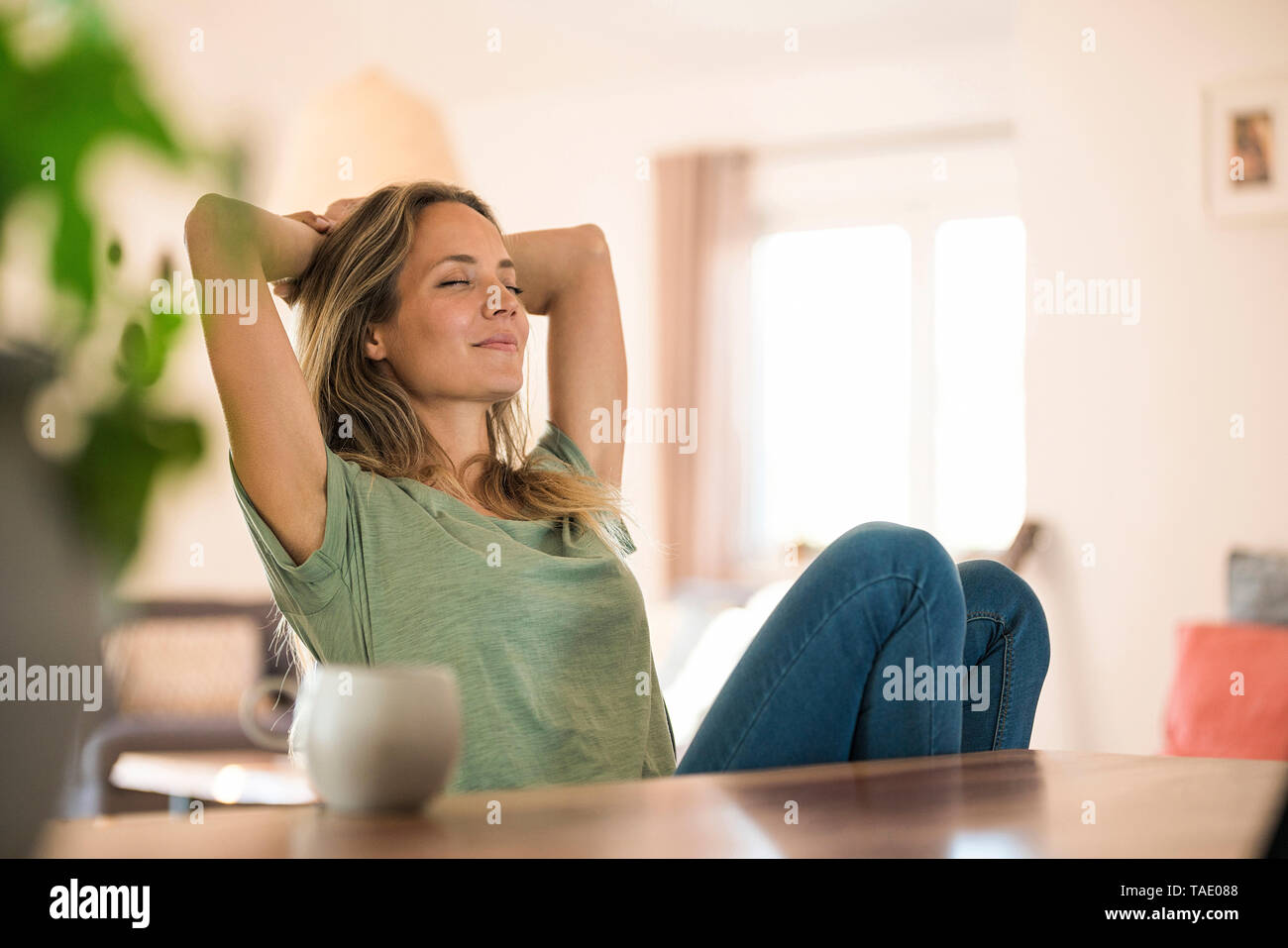 Woman sitting at dining table at home relaxing Stock Photo